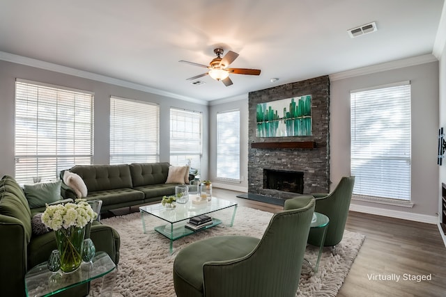 living area featuring a fireplace, wood finished floors, visible vents, and crown molding