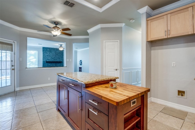 kitchen featuring a center island, crown molding, light tile patterned floors, visible vents, and butcher block countertops