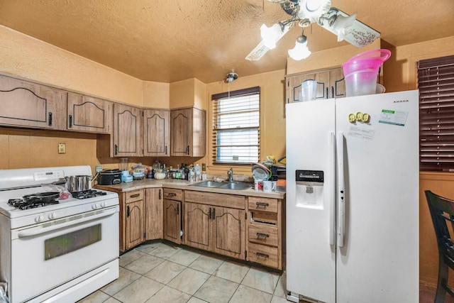 kitchen featuring light tile patterned flooring, white appliances, and sink