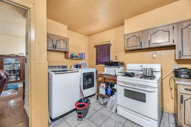 kitchen with light tile patterned flooring, white appliances, washer and clothes dryer, and a textured ceiling