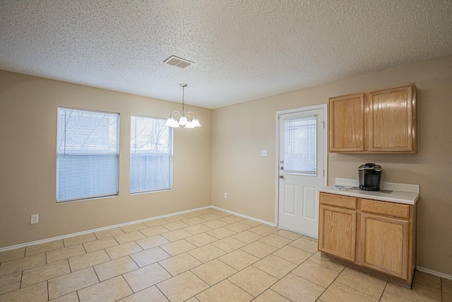 kitchen with pendant lighting, a notable chandelier, light tile patterned flooring, and a textured ceiling