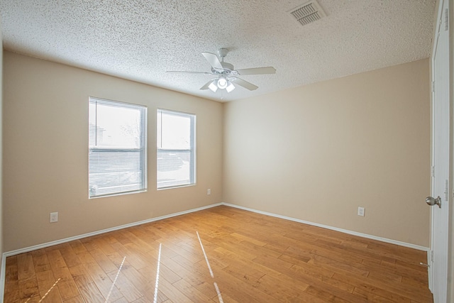 empty room with ceiling fan, light hardwood / wood-style flooring, and a textured ceiling