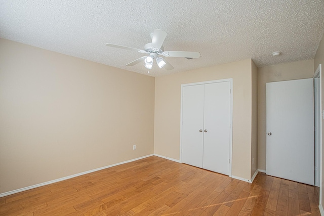 unfurnished bedroom featuring ceiling fan, a closet, light hardwood / wood-style floors, and a textured ceiling