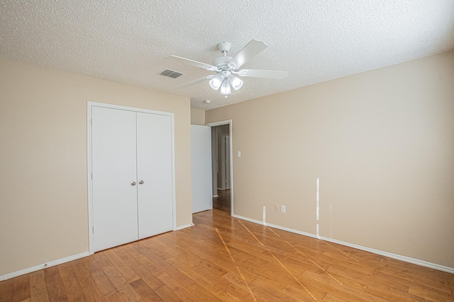 unfurnished bedroom featuring ceiling fan, a closet, a textured ceiling, and light hardwood / wood-style flooring