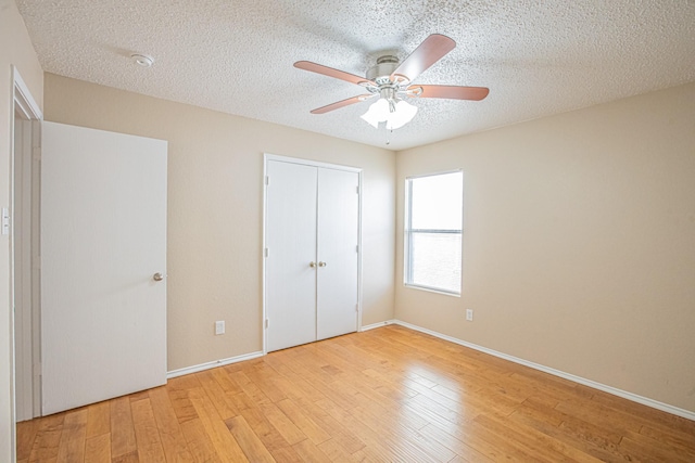 unfurnished bedroom featuring ceiling fan, light hardwood / wood-style floors, a textured ceiling, and a closet