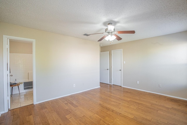 empty room with ceiling fan, light hardwood / wood-style floors, and a textured ceiling