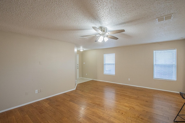 unfurnished room featuring ceiling fan, light hardwood / wood-style floors, and a textured ceiling