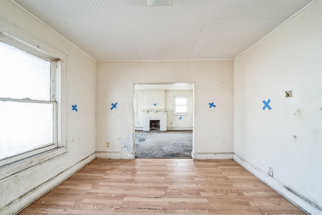 spare room with light hardwood / wood-style flooring and a brick fireplace