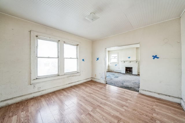 spare room featuring a fireplace and light hardwood / wood-style floors