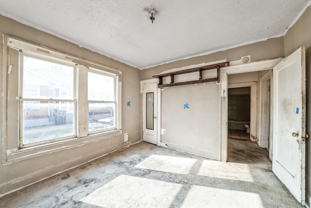 carpeted empty room with a textured ceiling