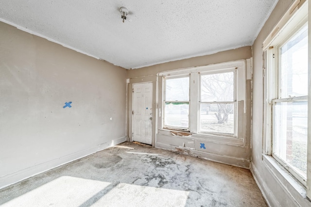 carpeted empty room featuring plenty of natural light and a textured ceiling