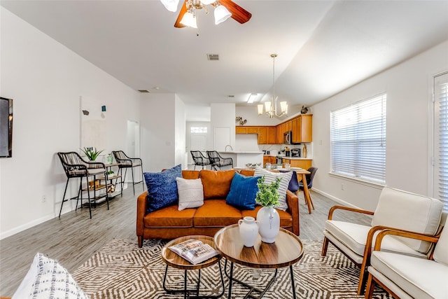 living room featuring ceiling fan with notable chandelier and light hardwood / wood-style floors