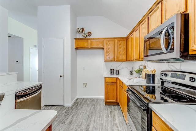 kitchen featuring lofted ceiling, light hardwood / wood-style floors, light stone countertops, and stainless steel appliances