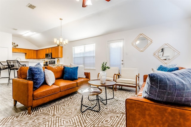 living room featuring ceiling fan with notable chandelier, light hardwood / wood-style floors, and lofted ceiling