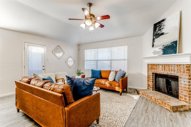 living room featuring light hardwood / wood-style flooring, a brick fireplace, ceiling fan, and lofted ceiling