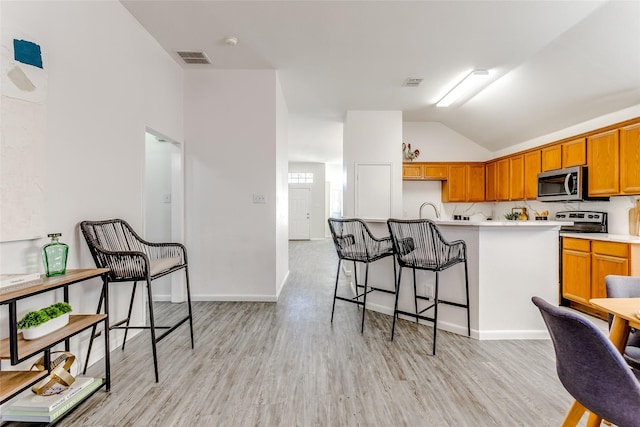 kitchen featuring a kitchen bar, light hardwood / wood-style flooring, vaulted ceiling, and sink