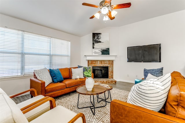 living room with hardwood / wood-style floors, vaulted ceiling, a brick fireplace, and ceiling fan