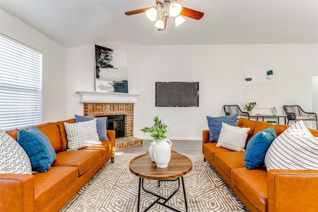 living room featuring ceiling fan, a fireplace, and light hardwood / wood-style flooring