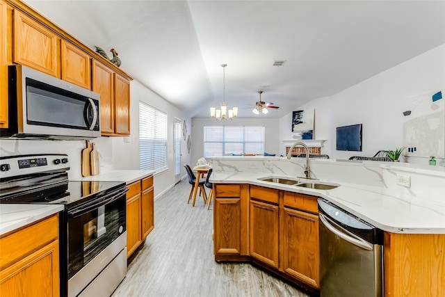 kitchen featuring appliances with stainless steel finishes, light wood-type flooring, ceiling fan with notable chandelier, vaulted ceiling, and sink