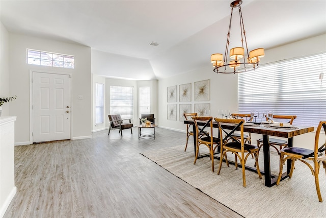 dining room featuring a chandelier, lofted ceiling, light hardwood / wood-style floors, and a healthy amount of sunlight