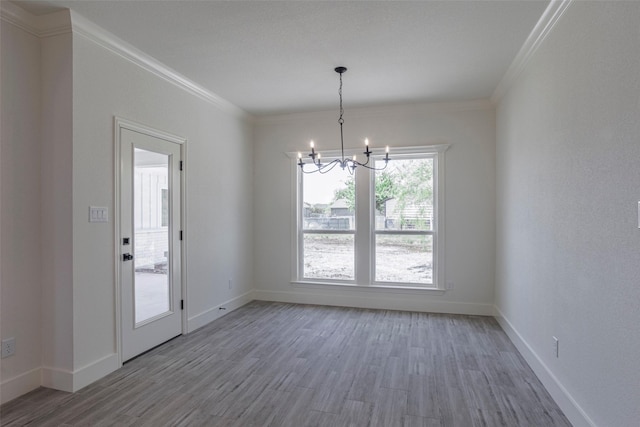 empty room with a chandelier, hardwood / wood-style floors, and ornamental molding