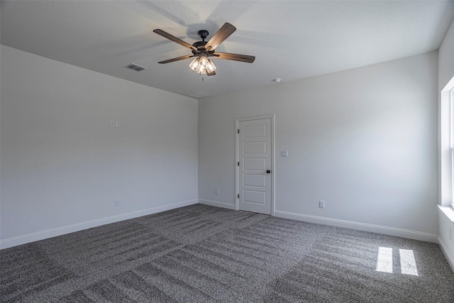 empty room featuring ceiling fan and dark colored carpet