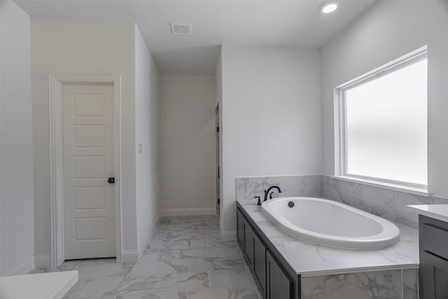 bathroom featuring vanity and tiled tub