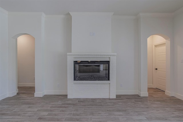 unfurnished living room featuring crown molding and a brick fireplace