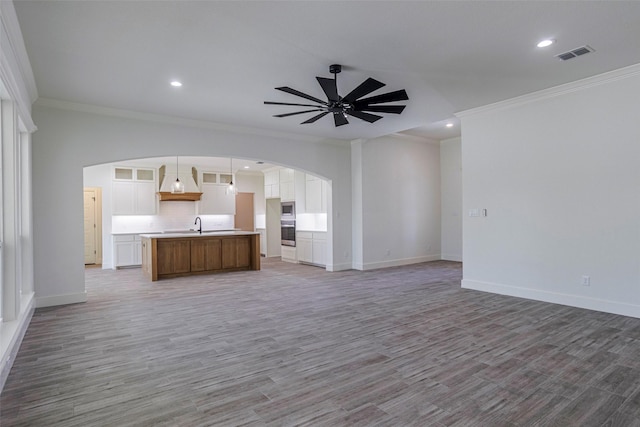 unfurnished living room with hardwood / wood-style floors, ceiling fan, and ornamental molding