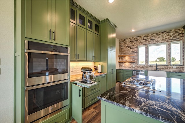 kitchen with sink, dark stone counters, green cabinetry, and appliances with stainless steel finishes