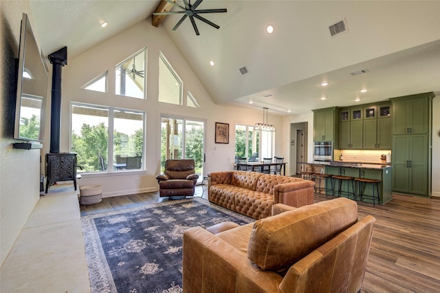 living room with beam ceiling, a wood stove, ceiling fan, and hardwood / wood-style floors