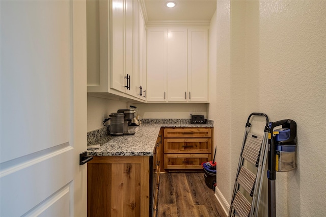 bar with white cabinetry, dark hardwood / wood-style flooring, and light stone counters