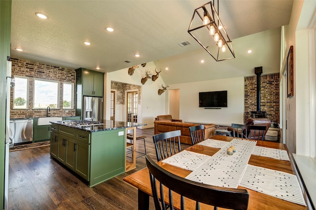 dining room with a wood stove, sink, dark wood-type flooring, brick wall, and a textured ceiling