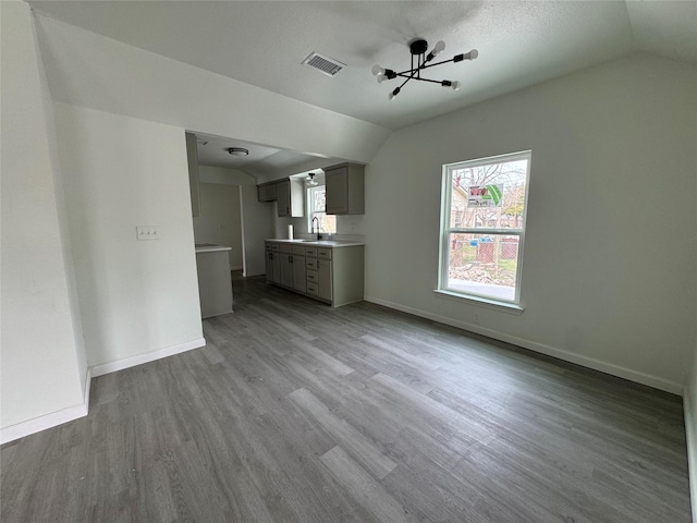 unfurnished living room featuring lofted ceiling, sink, and light wood-type flooring