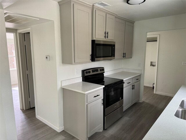 kitchen with stainless steel appliances, sink, dark hardwood / wood-style floors, and gray cabinetry