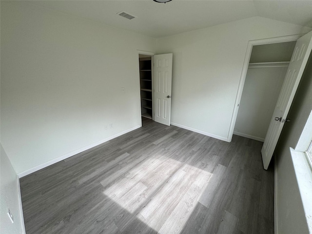 unfurnished bedroom featuring hardwood / wood-style floors, vaulted ceiling, and a closet