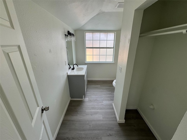 bathroom with lofted ceiling, toilet, a textured ceiling, vanity, and hardwood / wood-style floors