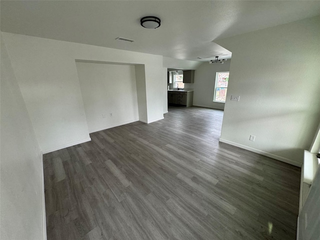 empty room with dark wood-type flooring and an inviting chandelier