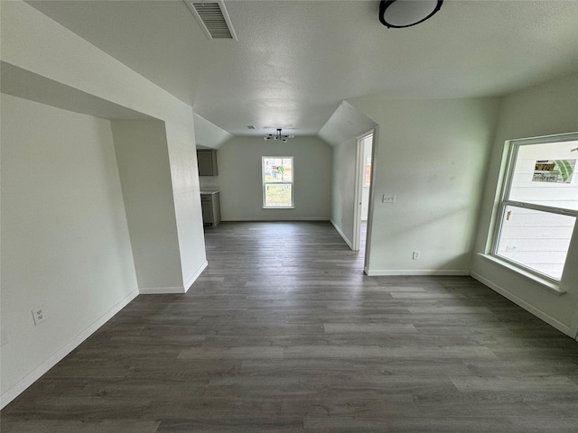 unfurnished living room featuring hardwood / wood-style flooring, vaulted ceiling, and a textured ceiling