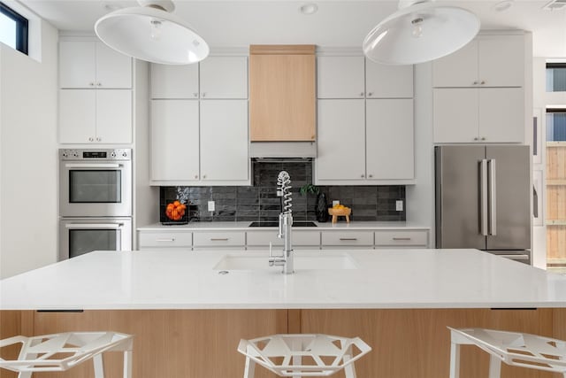 kitchen with a center island with sink, white cabinetry, stainless steel appliances, and a breakfast bar area