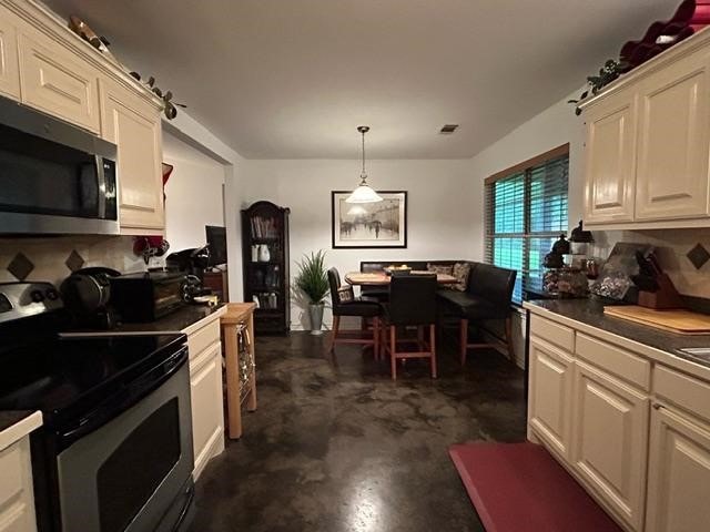 kitchen with cream cabinets, pendant lighting, and stainless steel appliances