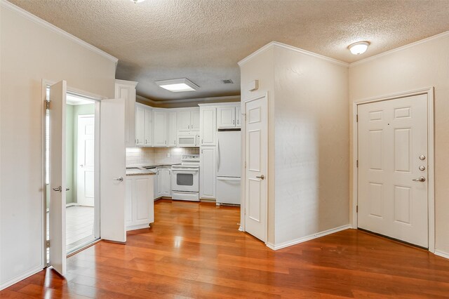 kitchen featuring white appliances, white cabinets, crown molding, decorative backsplash, and light wood-type flooring