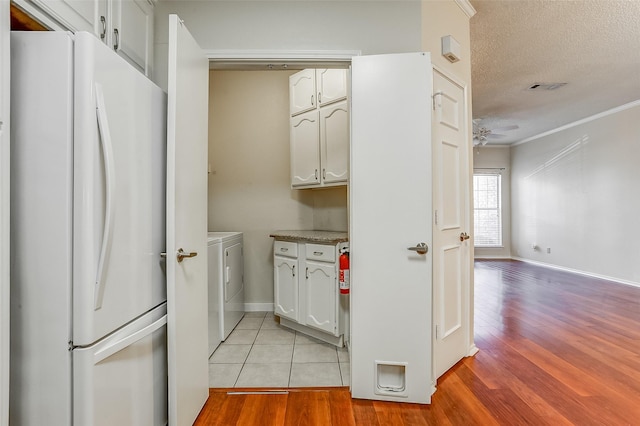 interior space featuring washing machine and clothes dryer, ornamental molding, a textured ceiling, and light wood-type flooring