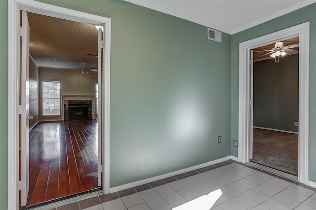 tiled spare room with a high end fireplace, a textured ceiling, and ornamental molding