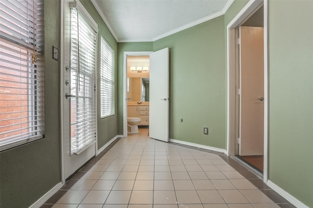 unfurnished bedroom featuring crown molding, connected bathroom, light tile patterned floors, and a textured ceiling