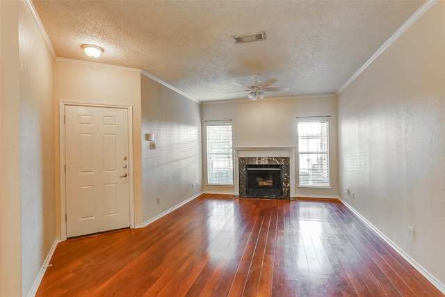 unfurnished living room with dark wood-type flooring, a textured ceiling, ornamental molding, ceiling fan, and a high end fireplace