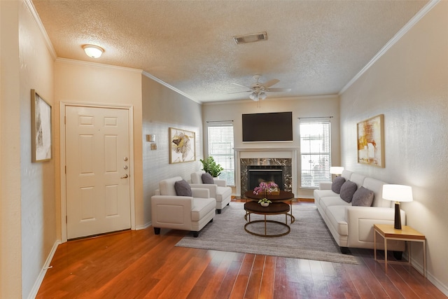 living room with wood-type flooring, ornamental molding, and a high end fireplace