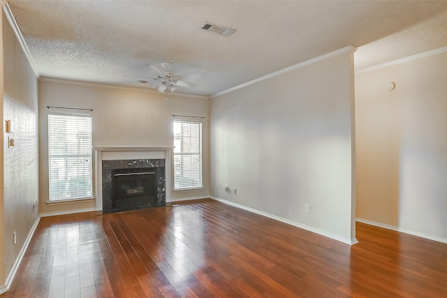 unfurnished living room featuring crown molding, ceiling fan, dark hardwood / wood-style floors, a fireplace, and a textured ceiling