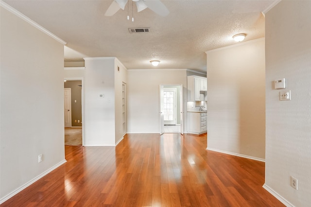 unfurnished living room with crown molding, hardwood / wood-style floors, ceiling fan, and a textured ceiling