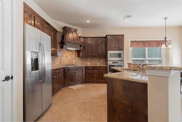 kitchen with tasteful backsplash, light stone counters, a notable chandelier, premium range hood, and appliances with stainless steel finishes